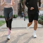 Fit couple jogging together on an urban sidewalk in sportswear.